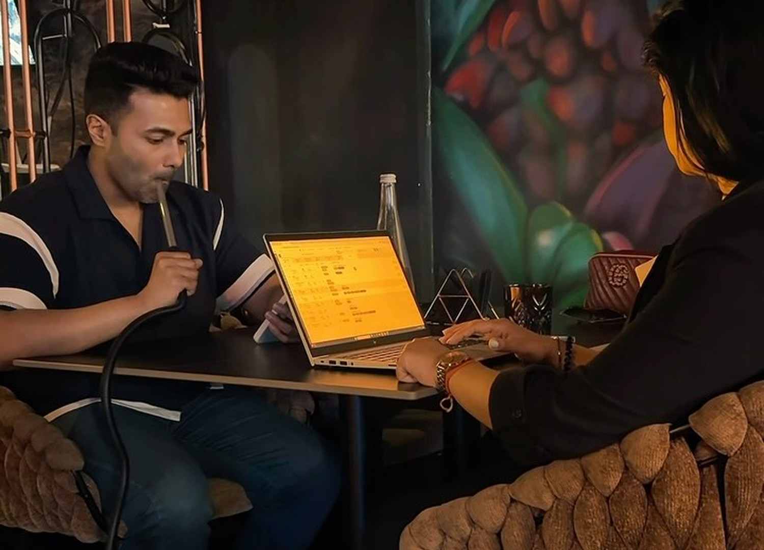 Young professionals working together in Korma Sutra’s coworking space, seated at wooden tables with laptops open, while enjoying shisha.