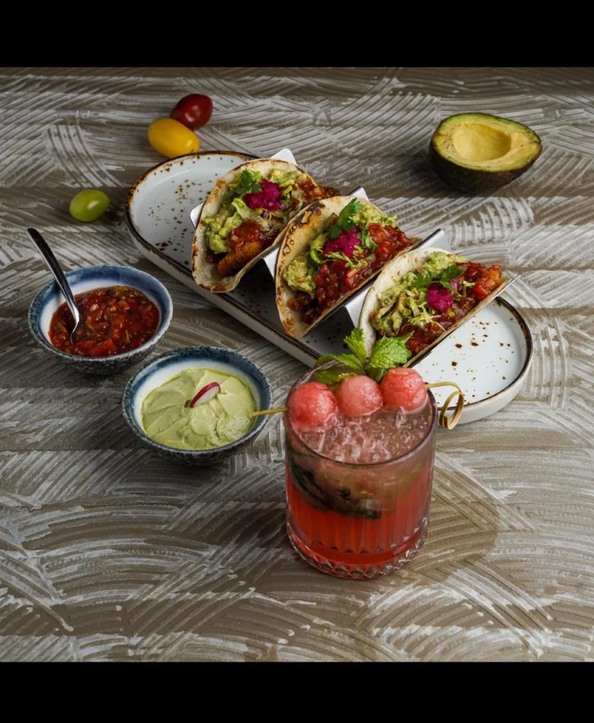 Plated Indian fusion tacos served with fresh dips and a crafted mocktail at a restaurant in Al Barsha